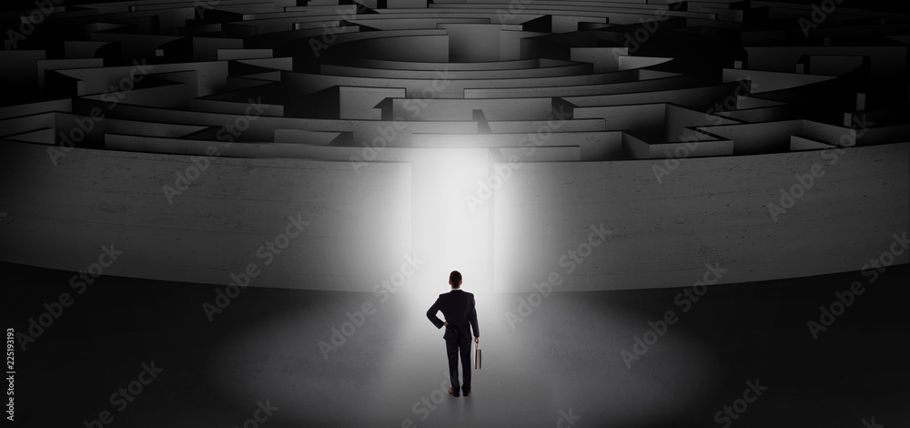 Businessman getting ready to enter a concentric labyrinth with lighted entrance concept

