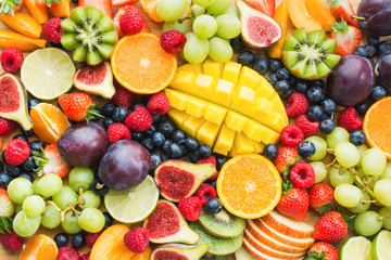 Assortment of healthy raw fruits and berries platter background, strawberries raspberries oranges plums apples kiwis grapes blueberries, mango, top view, selective focus