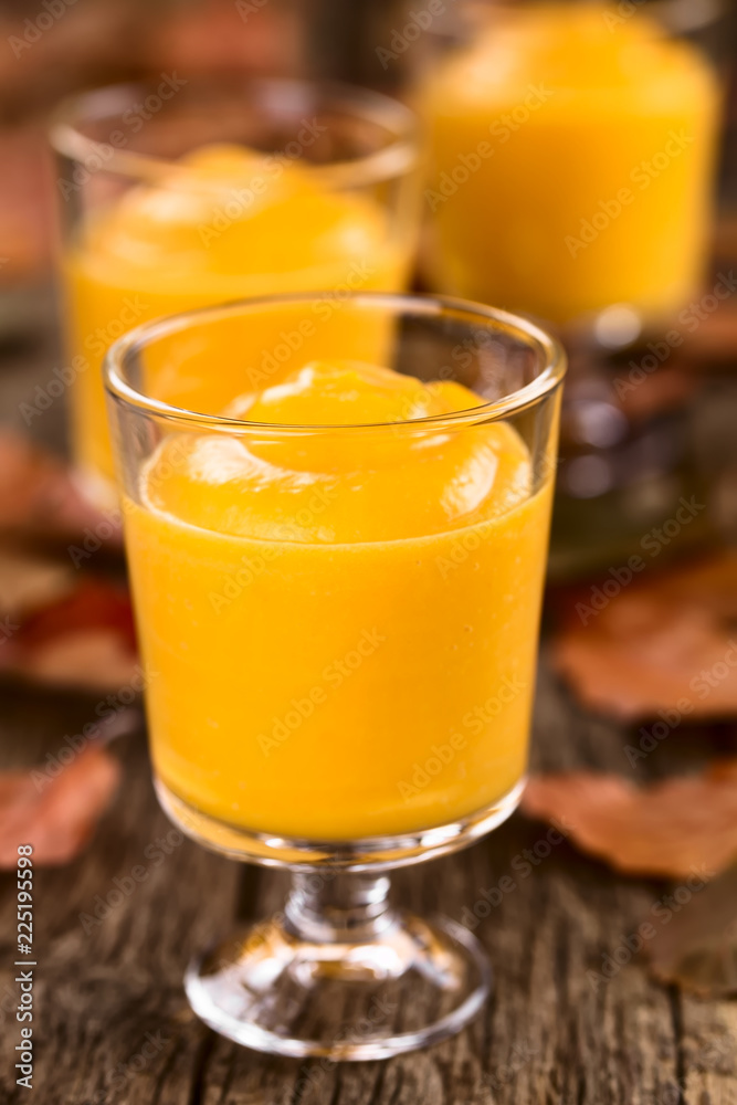 Hausgemachte Kürbismousse oder -pudding in Gläser, fotografiert auf rustikalem Holz (Selektiver Fokus, Fokus auf den vorderen Glasrand des ersten Desserts) Hausgemachte Kürbismousse oder -pudding in Gläser, fotografiert auf rustikalem Holz (Selektiver Fokus, Fokus auf den vorderen Glasrand des ersten Desserts)