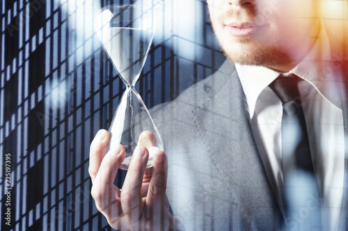 Businessman holding a hourglass. Concept of deadline in business