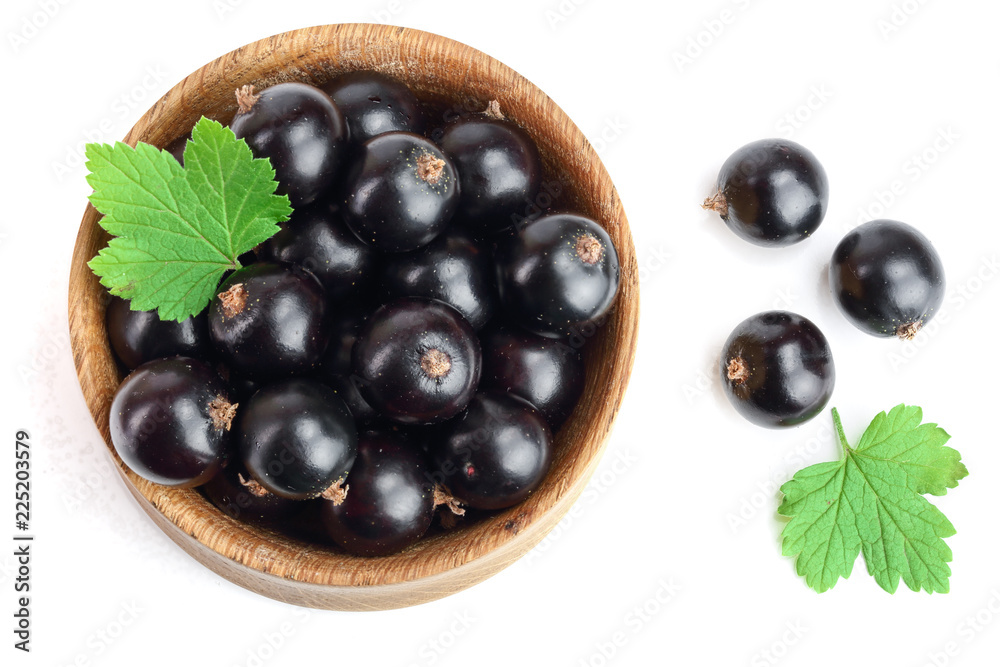 black currant with leaf in wooden bowl isolated on white background. Top view. Flat lay pattern black currant with leaf in wooden bowl isolated on white background. Top view. Flat lay pattern