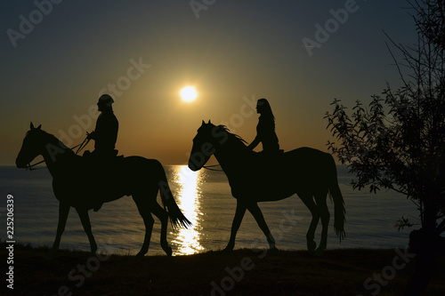 Two riders riding during sunset on the seashore © hibrida