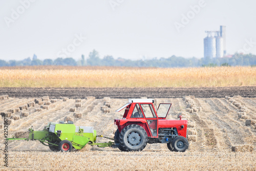 A man with a tractor makes bales of hay in the field