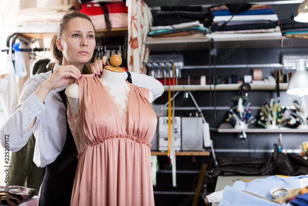 Woman is thinking about modern design near mannequin for new fashion collection