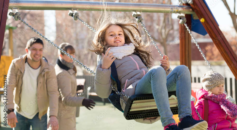 Fototapeta premium family with two girls having fun on swings outdoors