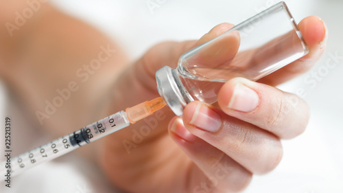 Macro image of nurse filling small syringe with drugs from vial