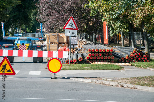 City district heating pipeline reparation and reconstruction parallel with the street with construction machinery and safety road traffic barrier around the excavation site with pipes