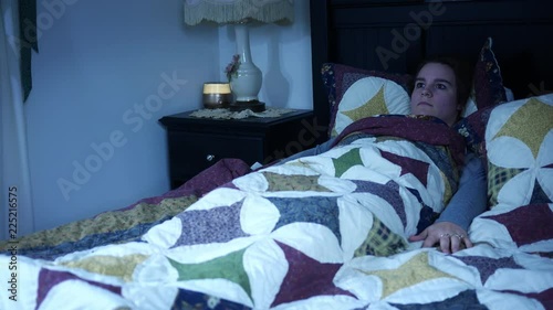 A woman experiencing sleep paralysis in dark bedroom