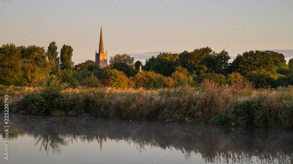 Beautiful dawn landscape image of River Thames at Lechlade-on-Thames in English Cotswolds countryside with church spire in background