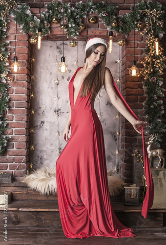 Sexy brunette girl in red v-neck long dress over new year's decorations.