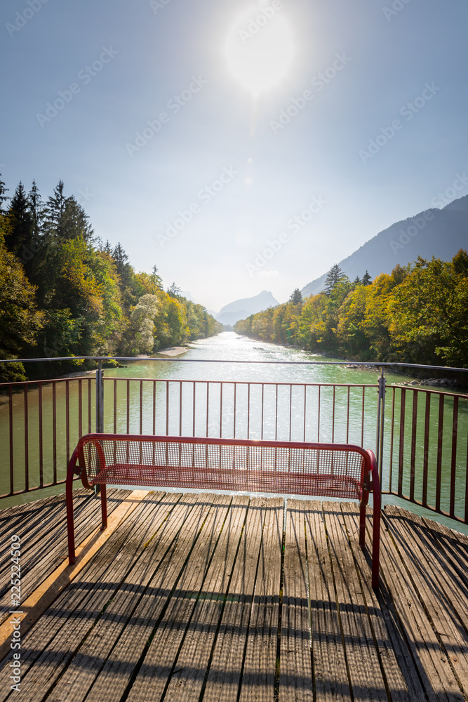 Farbenfrohe Spazierbank mit Aussicht auf Fluss und Wälder, Herbsttag, blauer Himmel