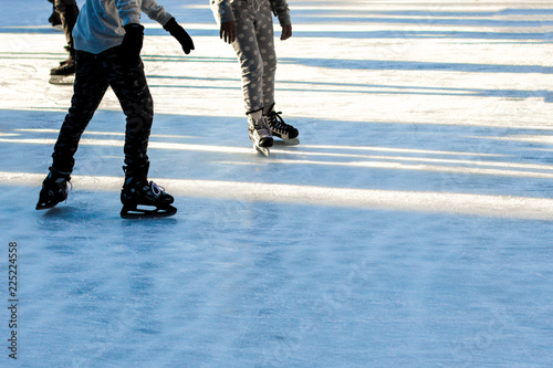 close-up of legs on skates in winter on an open skating rink, place for text/ The ice skates of two friends skating together on a winter afternoon/ Winter time, outdoor activities - concept