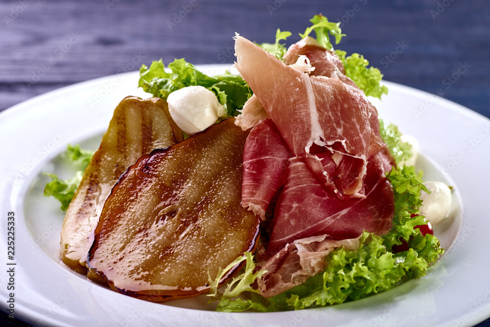 Expensive Italian, Spanish, French salad for festive table. Snack from pear, mozzarella, jamon, greens, lettuce, sauce. Cuisine of France, Spain, Italy. Photo of food for menu, cookbook, culinary blog Expensive Italian, Spanish, French salad for festive table. Snack from pear, mozzarella, jamon, greens, lettuce, sauce. Cuisine of France, Spain, Italy. Photo of food for menu, cookbook, culinary blog