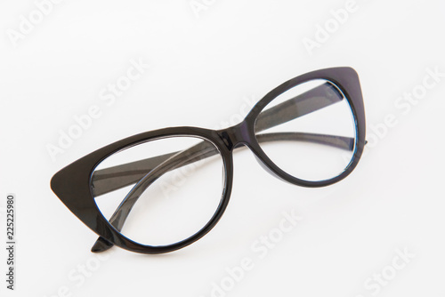 Pair of reading glasses or spectacles with modern dark frames folded up on a white background