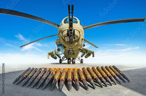 Military helicopter is parked, in the foreground the cartridges are the weapons that it shoots.