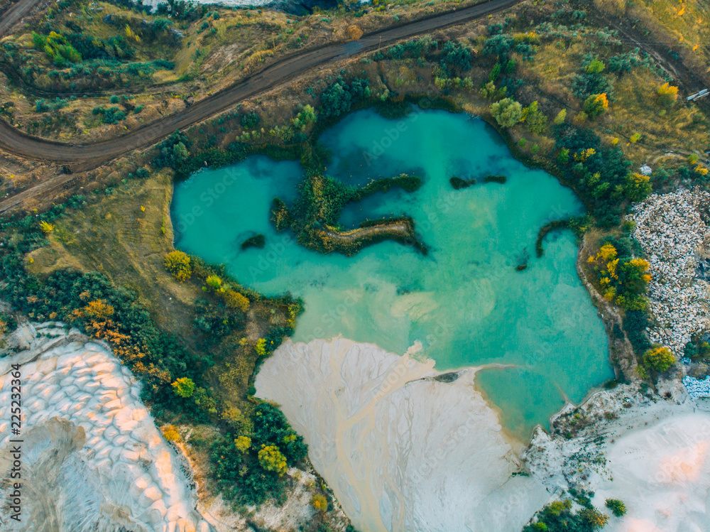Turquoise water in lake near chalk quarry and green forest, top view