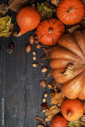 Autumn composition with dry leaves and ripe pumpkins on a dark wooden table. Top view. Copy space