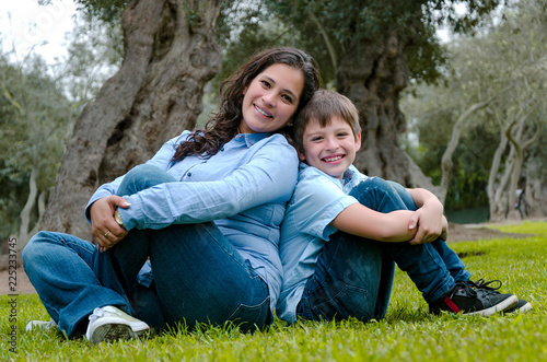 Mom and son sitting on green grass in green park. Concept of happy family relations