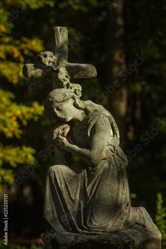 Sculpture of a Woman kneeling on a Cross - Tombstone on a Cemetery in Berlin, Germany