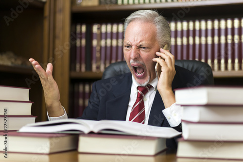 Angry businessman yelling on the cellphone while reading a book photo