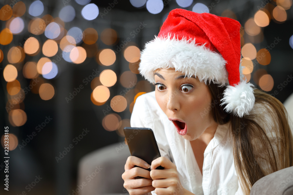 Amazed woman reading phone content in christmas Amazed woman reading phone content in christmas