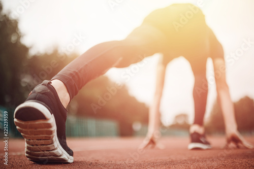 Runner athlete feet running on treadmill closeup on shoe, sunset