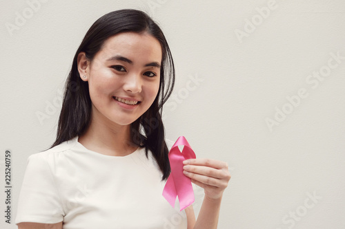 Asian young woman holding pink ribbon, breast cancer awareness, October pink concept