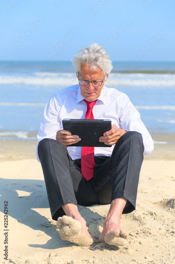 Business man working on tablet at the beach