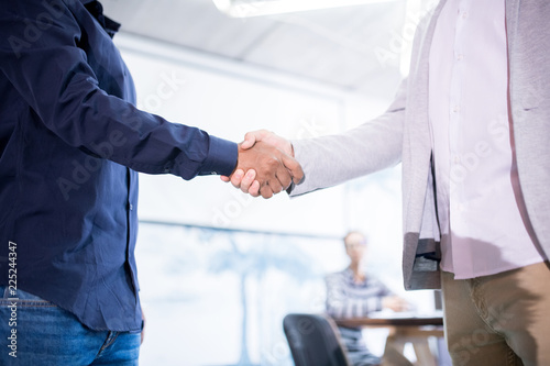 Staring business partnership: close-up of unrecognizable men making handshake while congratulating each other with successful deal