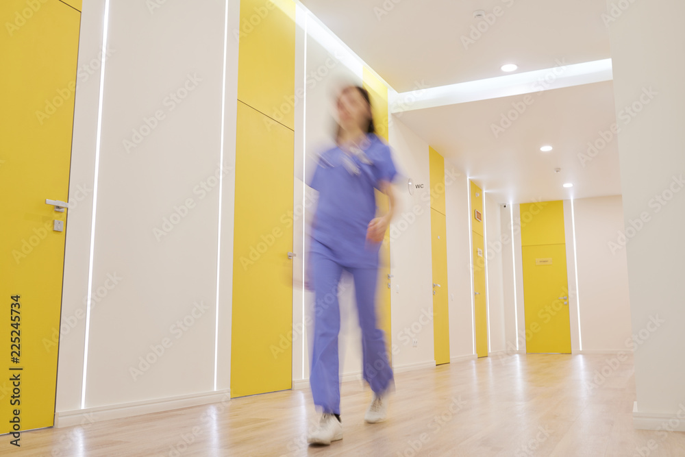 Wide angle view at corridor in modern clinic with blurred shape of nurse walking by, copy space