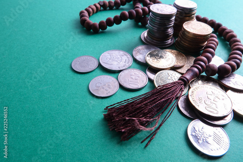 Islamic Banking/Financing Conceptual with rosary and coins on a green background.