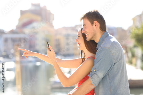 Couple checking phone pointing away on vacation
