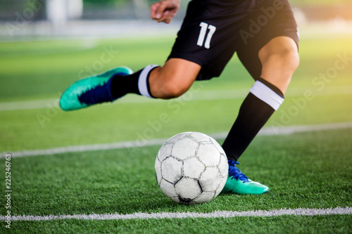 Soccer player speed run to shoot ball to goal on artificial turf.