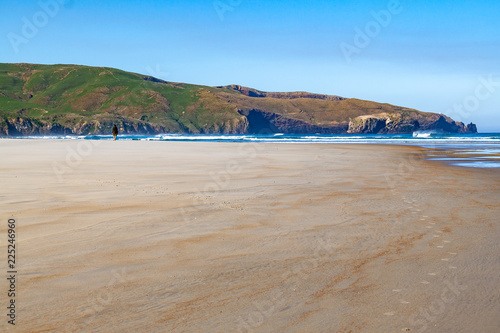 Person walking on beach towards the hills