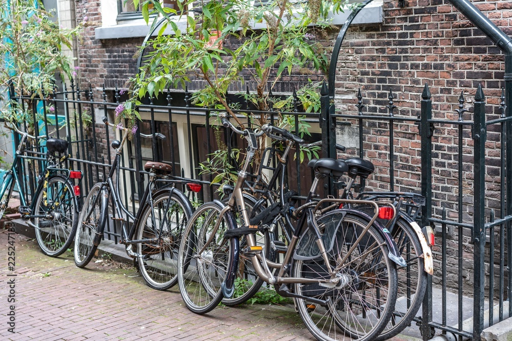 Alte Fahrräder angelehnt an geschmiedeten Eisenzaun, dahinter eine backsteinziegel Häuserfront 
