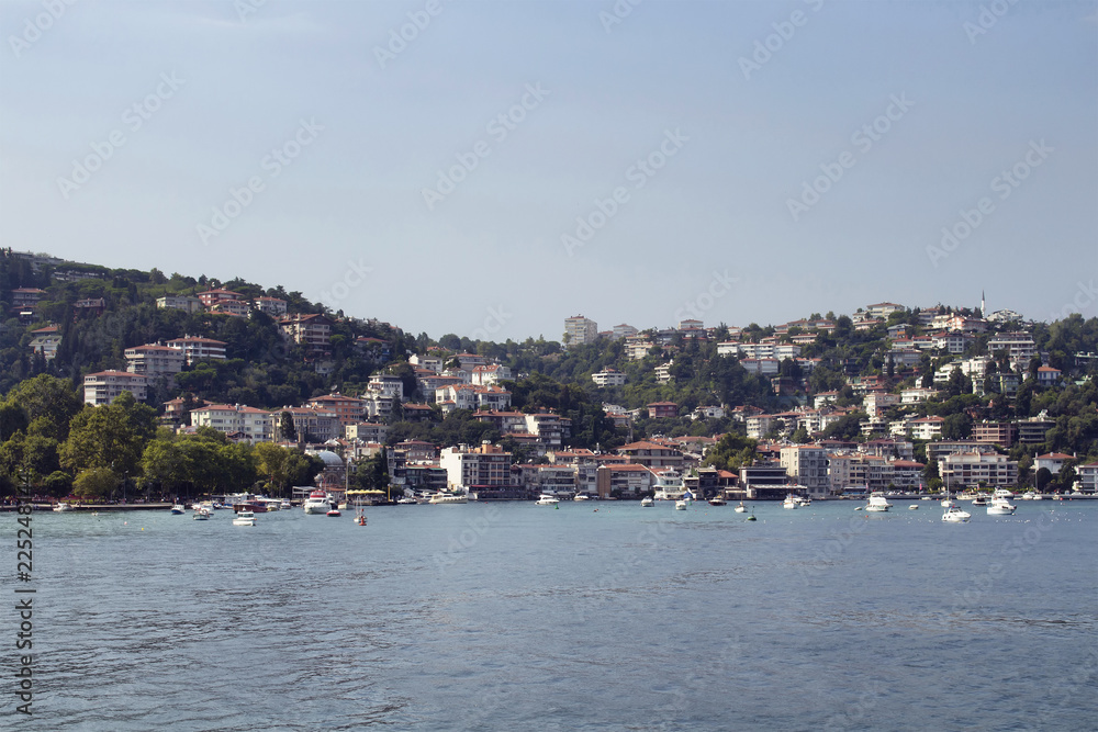 View of motorboats and yachts, buildings on European side and Bosphorus in Istanbul. It is a sunny summer day.