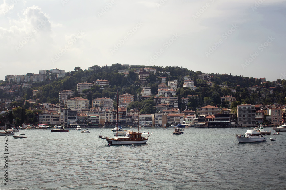 View of motorboats and yachts, buildings on European side and Bosphorus in Istanbul. It is a sunny summer day.