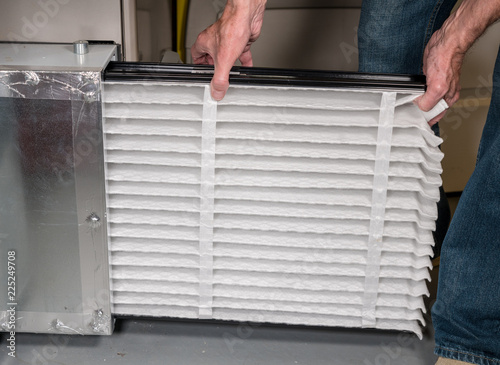 Fototapet Senior man inserting a new air filter in a HVAC Furnace