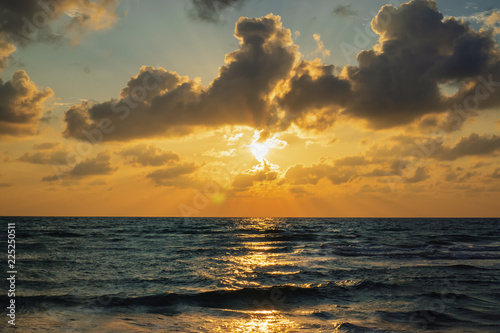 Sunbeam through cloud formation on ocean horizon during sunset.