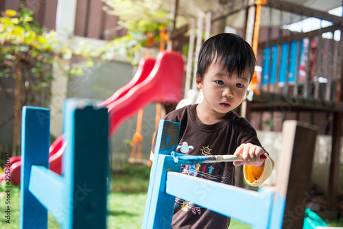 A young boy painting furniture in the garden
