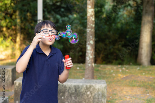 boy blowing soap bubbles in the park
