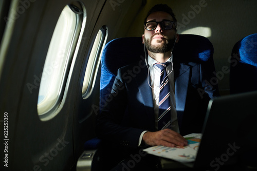 Portrait of successful businessman sleeping during long flight in dimly lit plane, copy space © Seventyfour