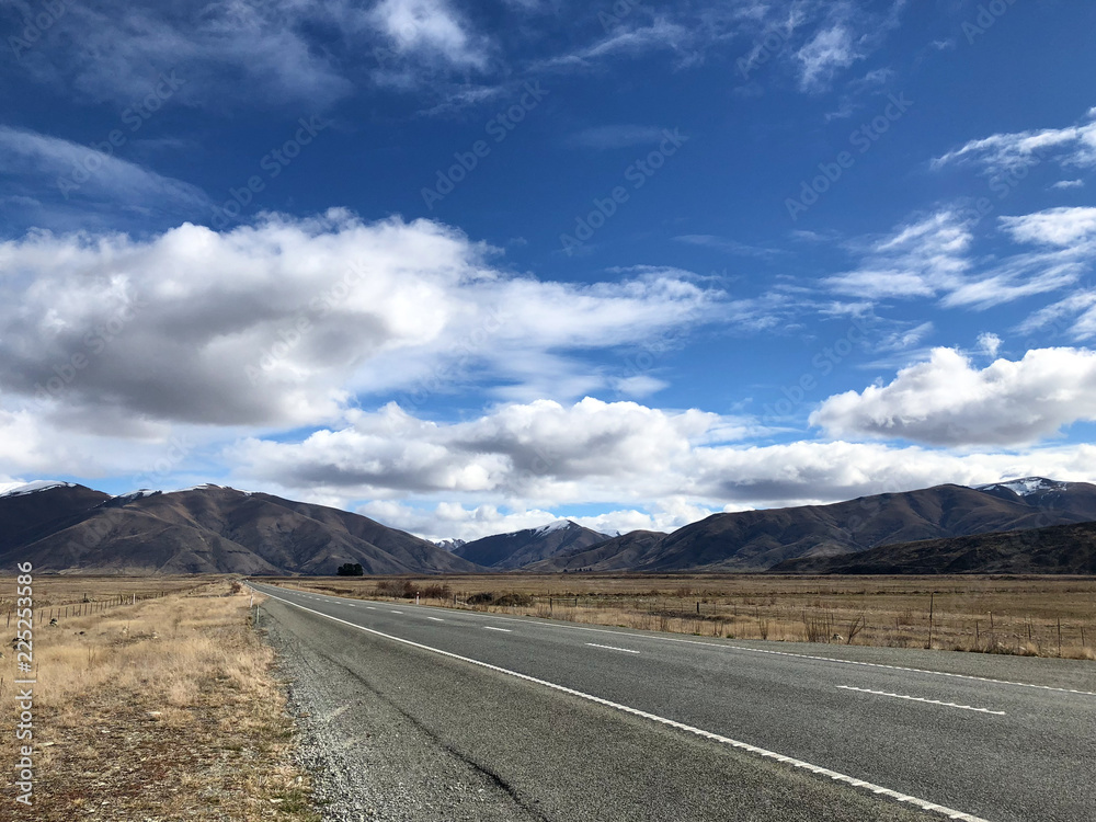 Straight road leading to Mountains and blue sky and white clouds in New Zealand