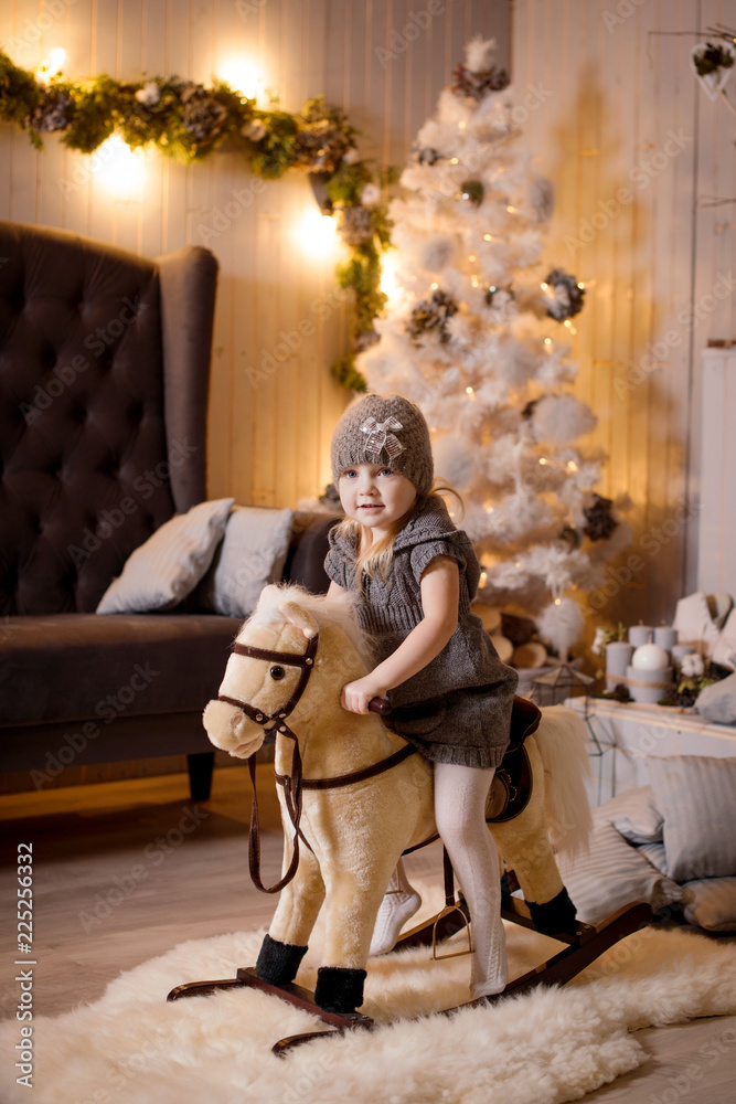 A little pretty girl celebrates a new year or Christmas in a cozy interior. Portrait of a girl on a Christmas decor background.