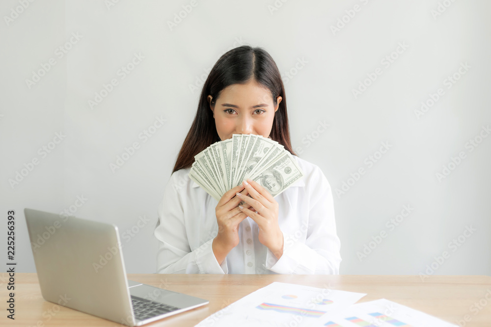 Successful beautiful Asian business young woman holding money US dollar bills in hand on office desk, business concept Successful beautiful Asian business young woman holding money US dollar bills in hand on office desk, business concept