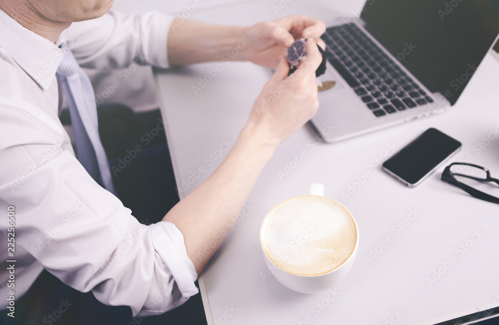 Φωτογραφία Young businessman trader sits at a table in the morning in a room near a laptop with a Cup of coffee