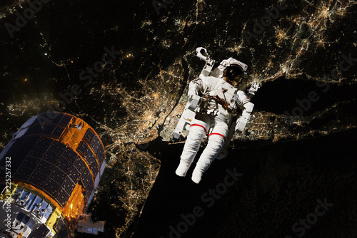Fototapeta Naklejka Na Ścianę i Meble -  astronaut flying in open space over the USA during night, near earth. Image made of NASA photos f
