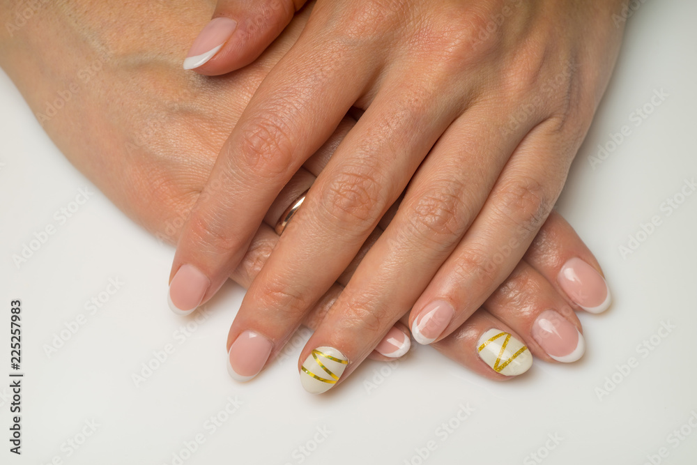 French manicure and nail gel Polish. The decoration of the nail white and gold decor. Top view Close-up photography French manicure and nail gel Polish. The decoration of the nail white and gold decor. Top view Close-up photography