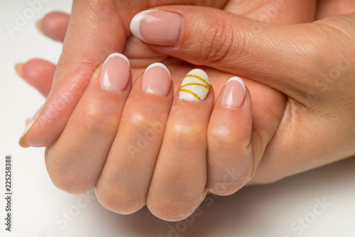 French manicure and nail gel Polish. Young, perfect, groomed woman's hands with pink and white nail varnish bottles.