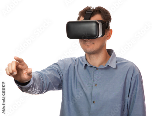 Man in Viara wearing glasses in shirt on white isolated background. Helmet virtual reality gadget concept. Man points finger on the virtual display